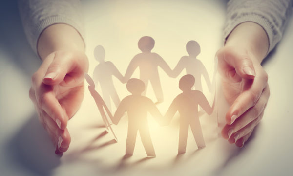 A woman's hands holding a group of paper people representing a nonprofit organization.