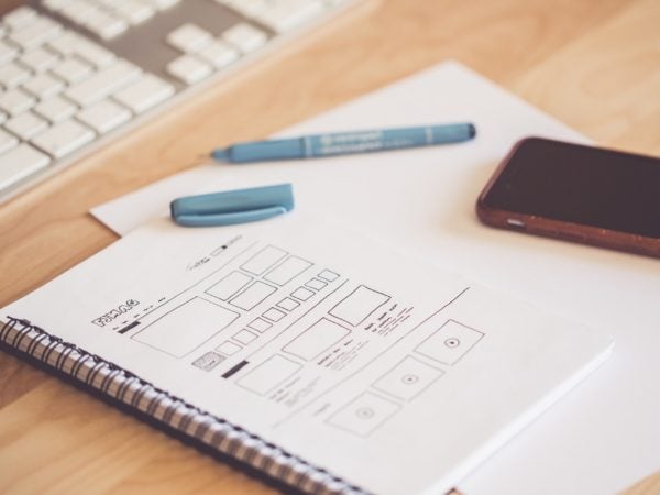 A notebook on an architect's desk next to a cell phone and keyboard.