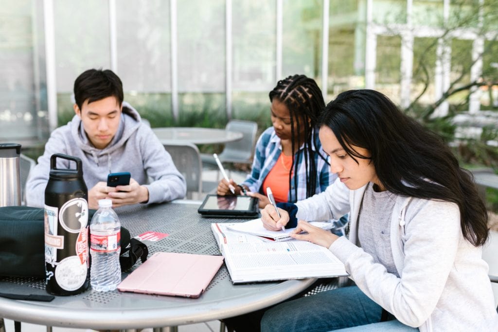 A group of students engaged in outdoor education at a table.