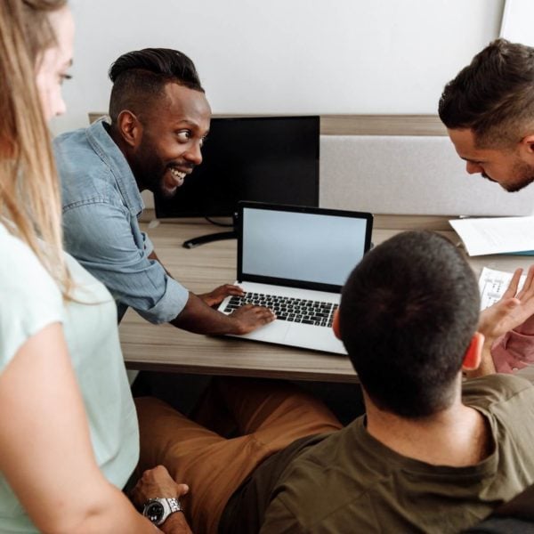 A group of people looking at a laptop in an office.